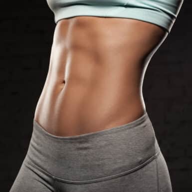 woman with abs and stomach showing on dark backdrop