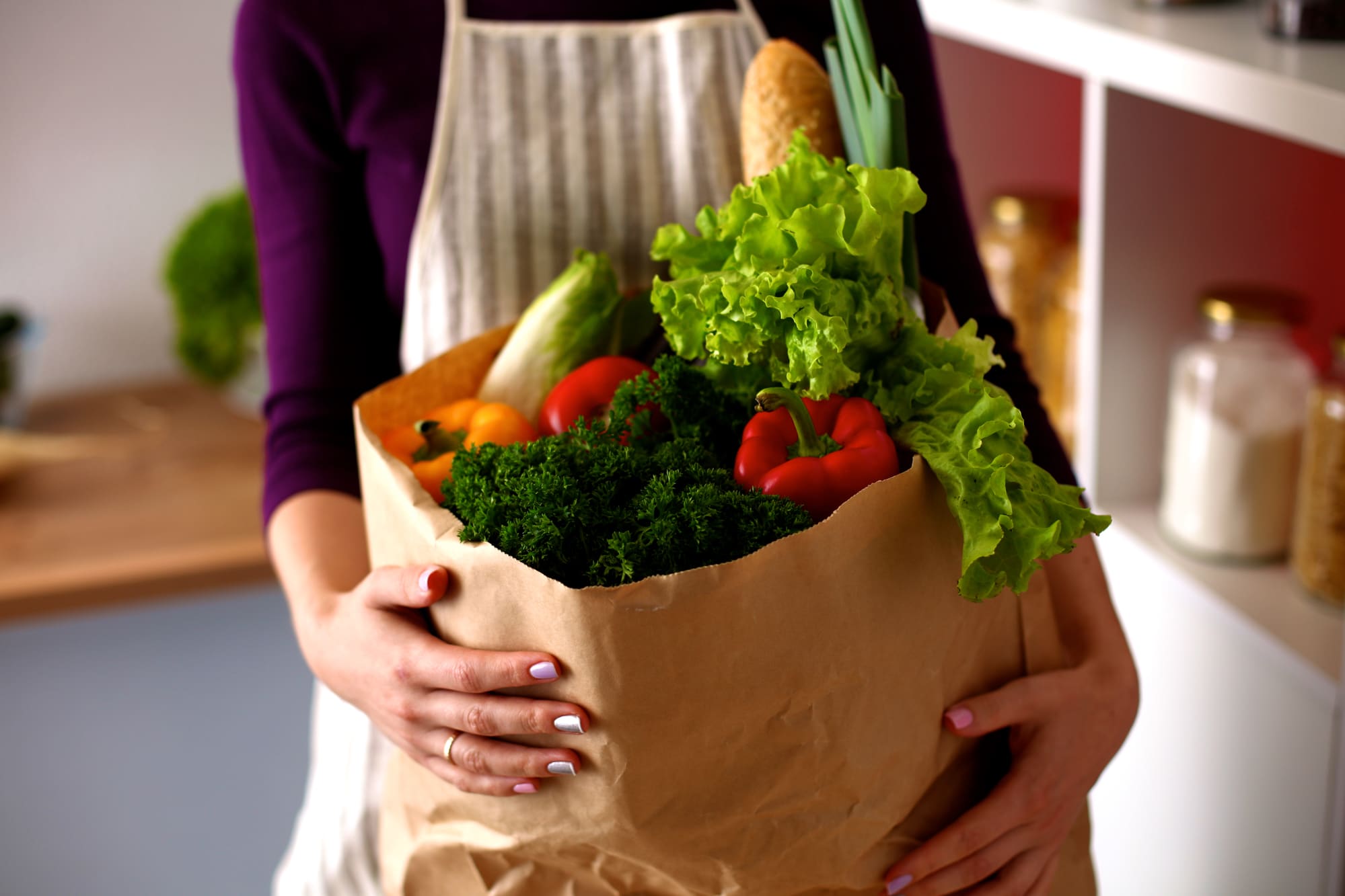 woman holding brown bag of healthy groceries