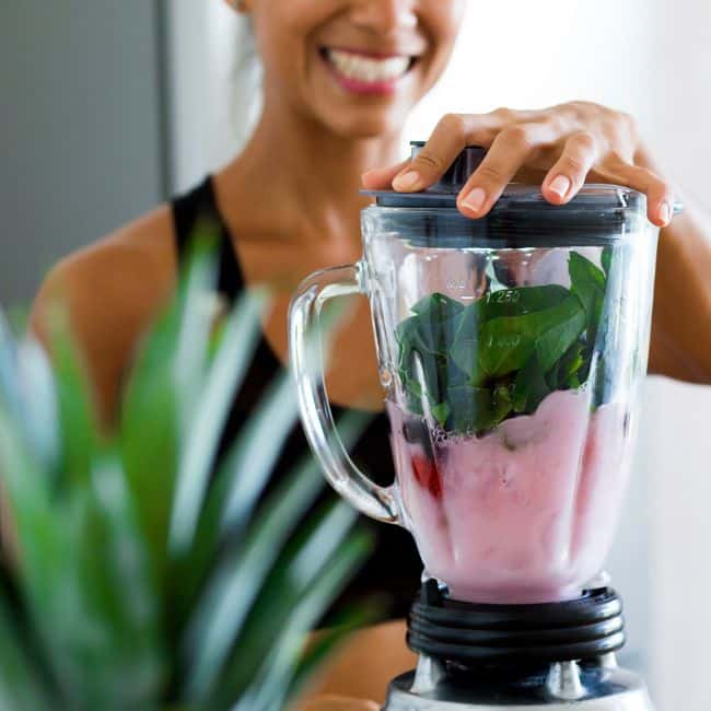 woman smiling looking at smoothie with healthy portions of nutrition that helps to lose weight without dieting