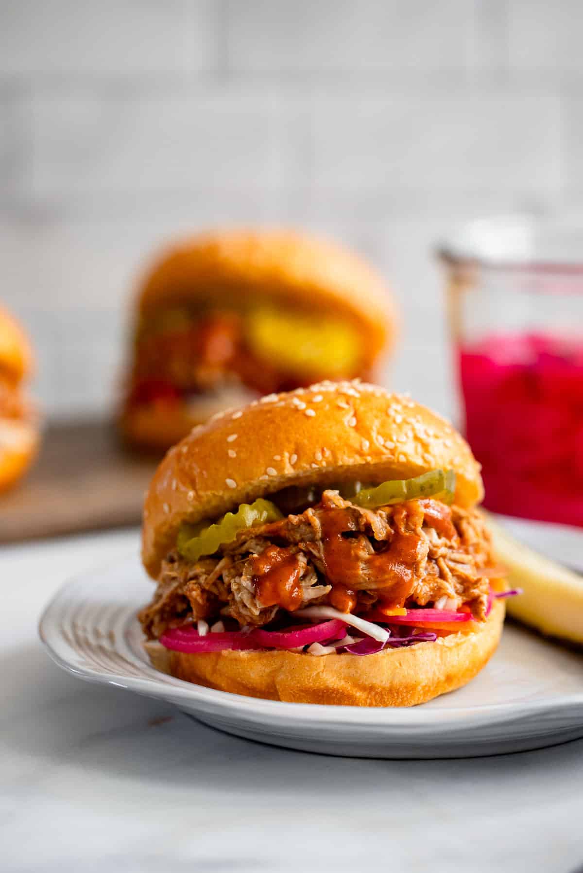 healthy crockpot pulled pork sandwich on white plate with pickle