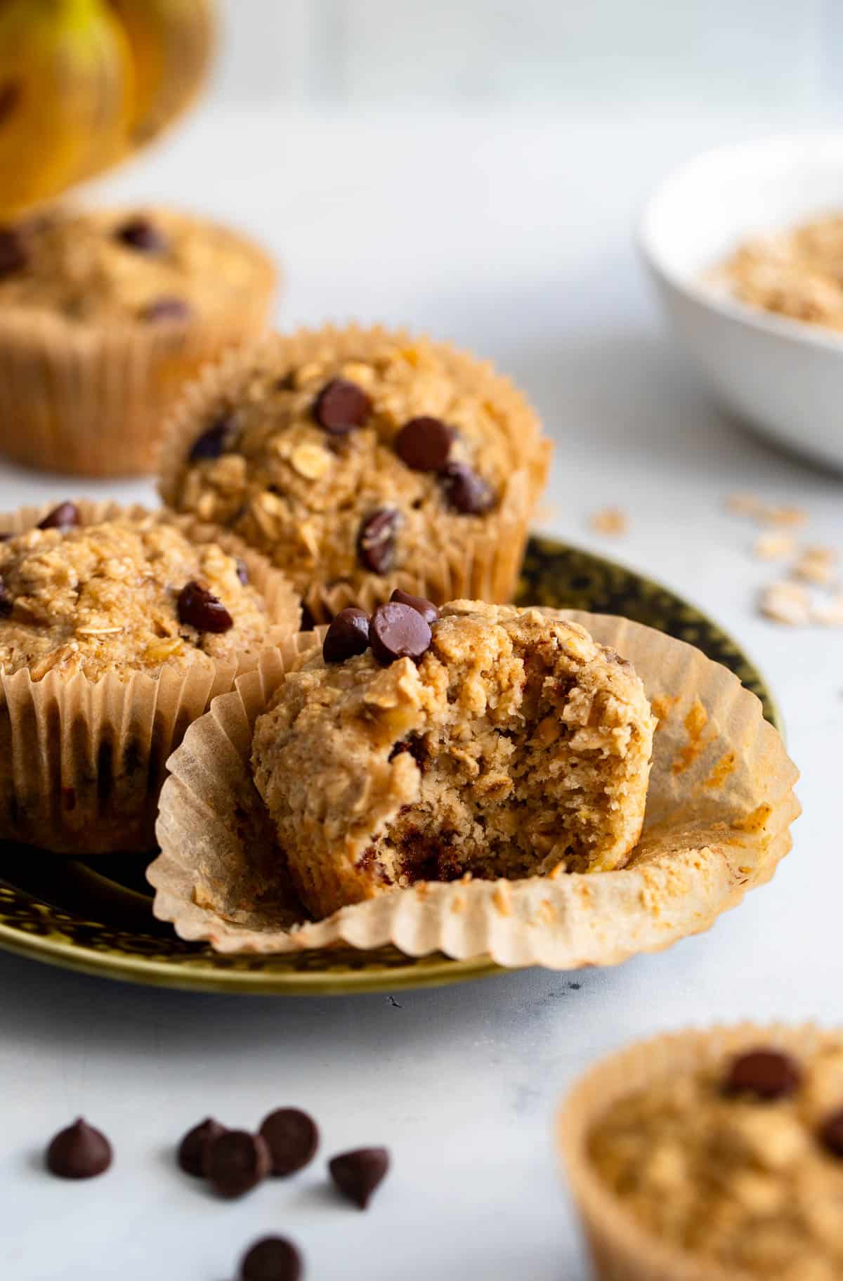healthy oat flour banana muffins on plate with bite taken from one