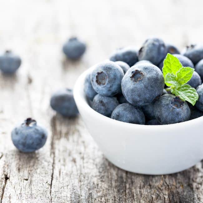 small bowl of blueberries on wooden table, best foods that lower cholesterol