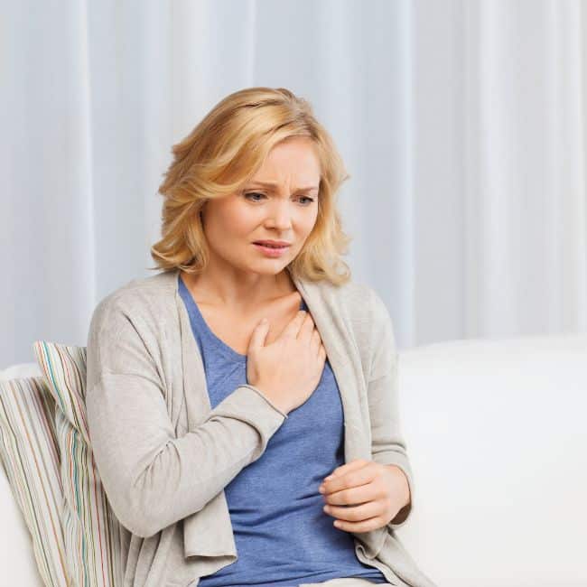 woman holding chest with worried look on her face