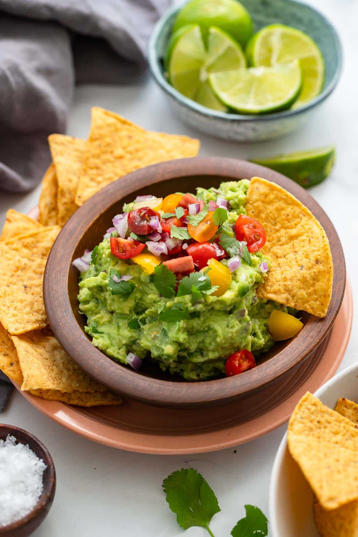 bowl of healthy guacamole with chips and sliced limes