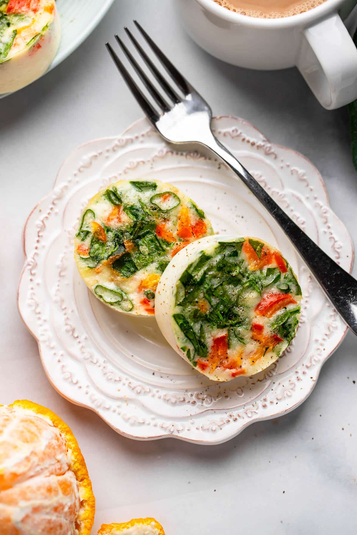 close up shot of healthy egg white bites with spinach and red pepper on white plate