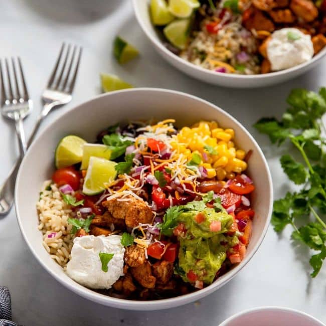 serving of healthy chicken burrito bowl with fresh toppings and cilantro