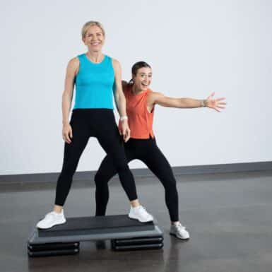 two women smiling on step aerobics platform
