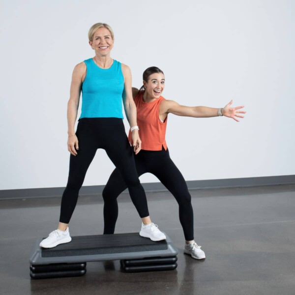 two women smiling on step aerobics platform