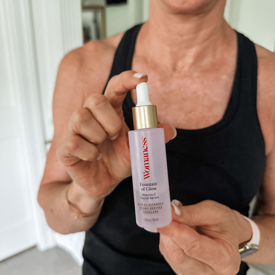 Woman holding onto a bottle of Womaness Foundation of Glow Vitamin C Serum
