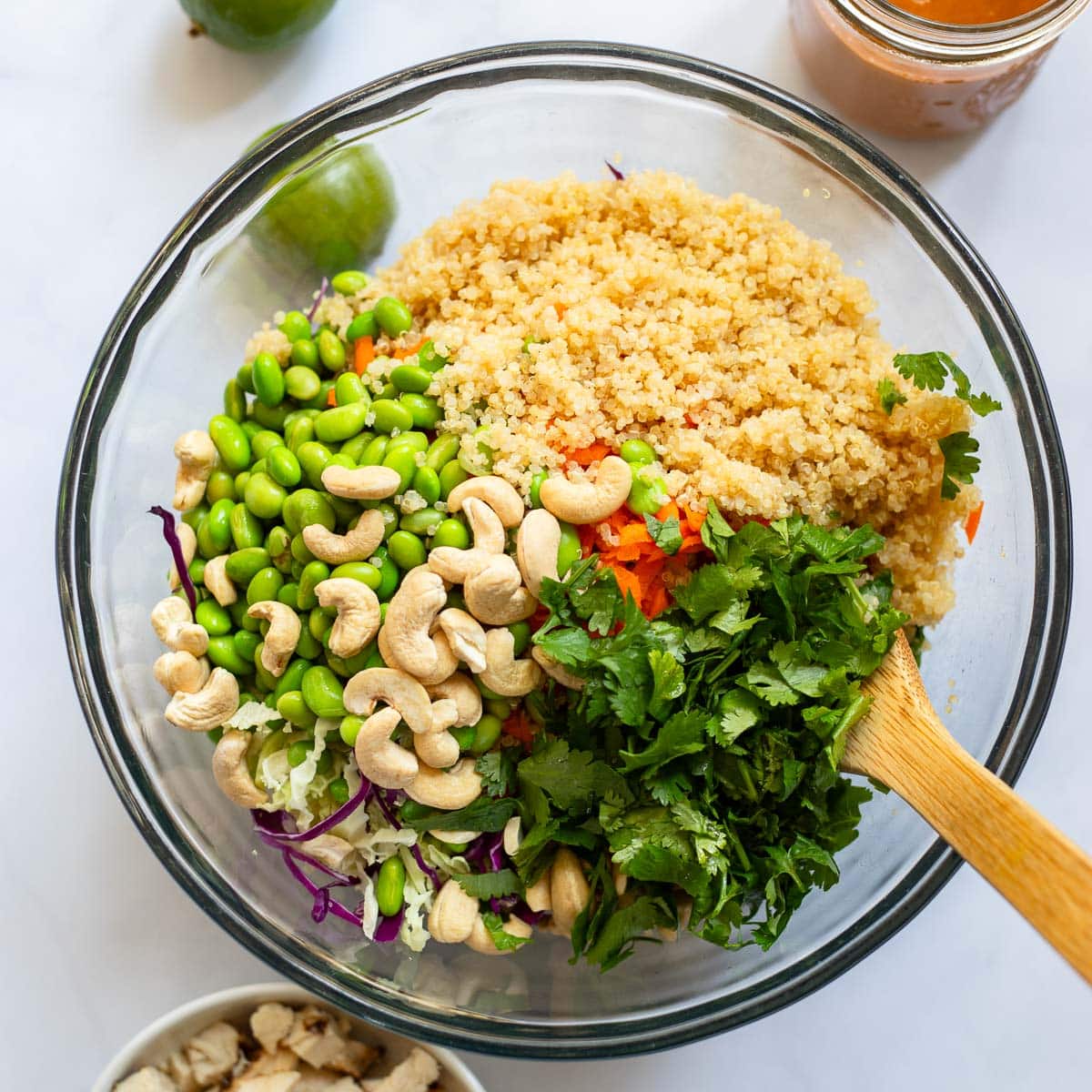 mixing crunchy cashew thai quinoa salad in glass bowl