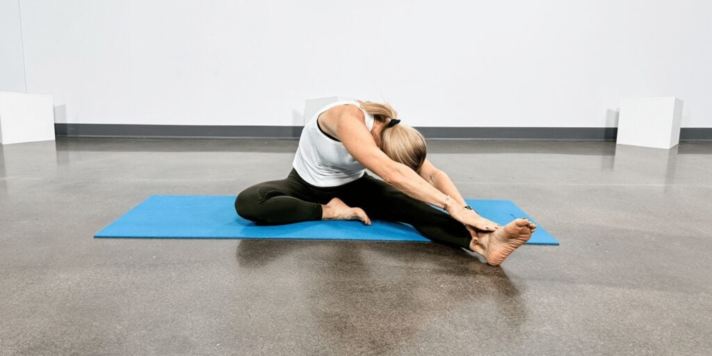 woman doing yoga poses for back pain, seated single leg forward fold.