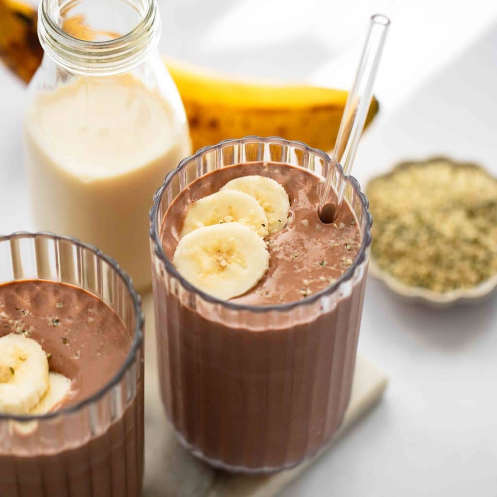 Chocolate and banana smoothie prepared in a glass cup with a straw