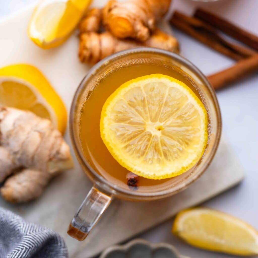 Top view of ginger and turmeric tea with lemon garnish in a glass cup