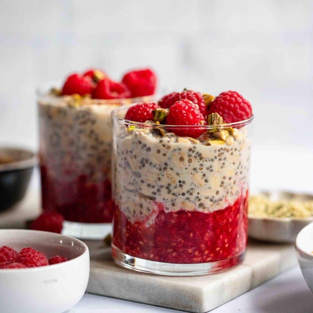 vanilla overnight oats prepared in glass jar with raspberry toppings