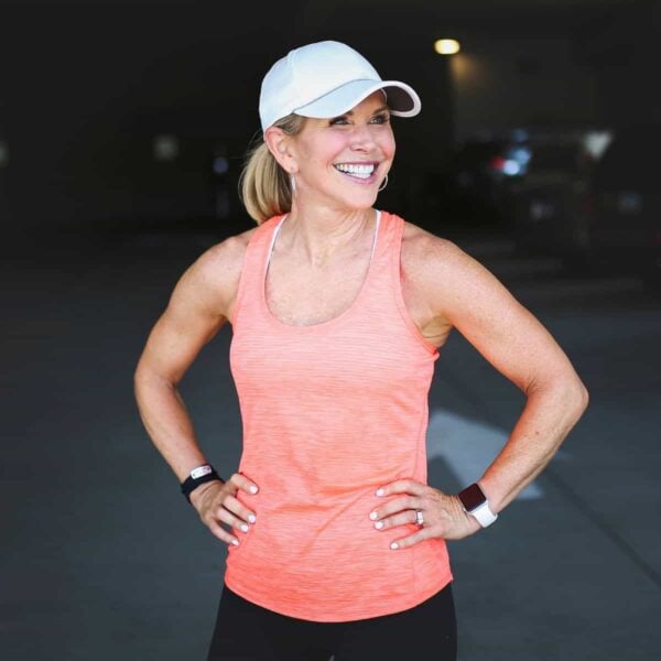 Smiling woman wearing an orange athletic tank top.