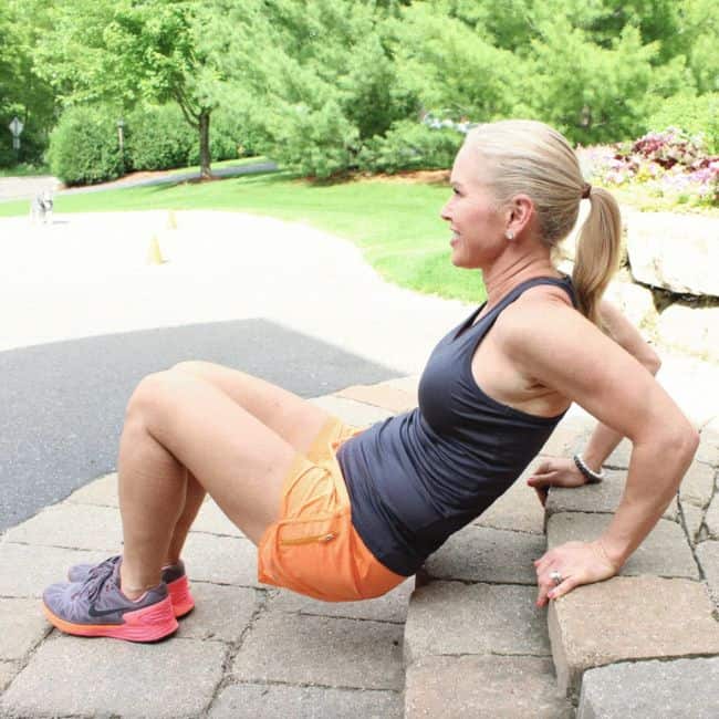Woman exercising on outdoor steps, smiling.