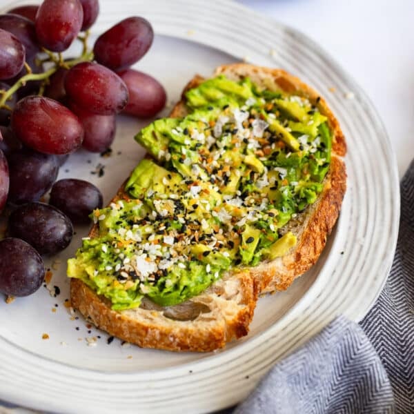 everything bagel avocado toast served on plate with grapes