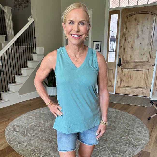 woman wearing teal top that covers menopause belly fat from Amazon smiling indoors