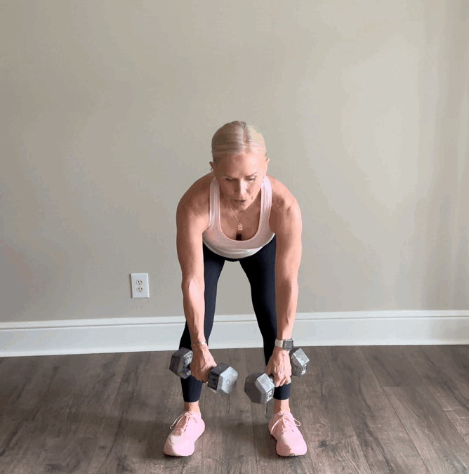 Woman performing a dumbbell exercise indoors.