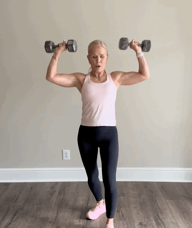 Woman lifting dumbbells in a home workout.