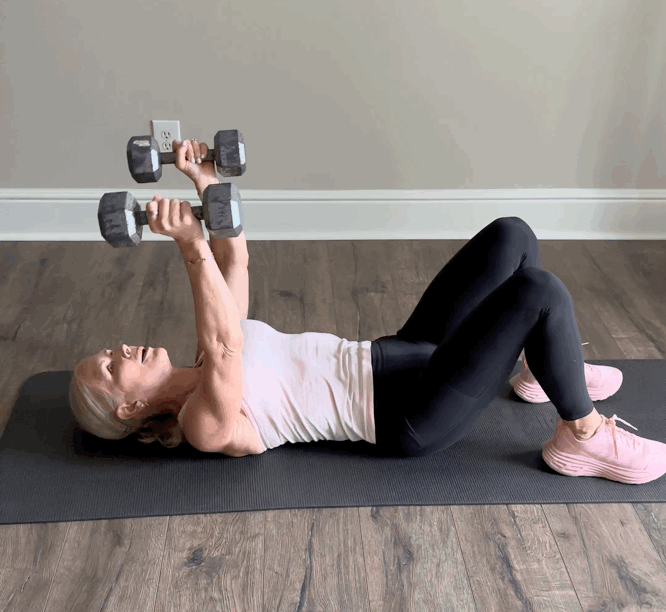 Person performs dumbbell exercise on yoga mat.