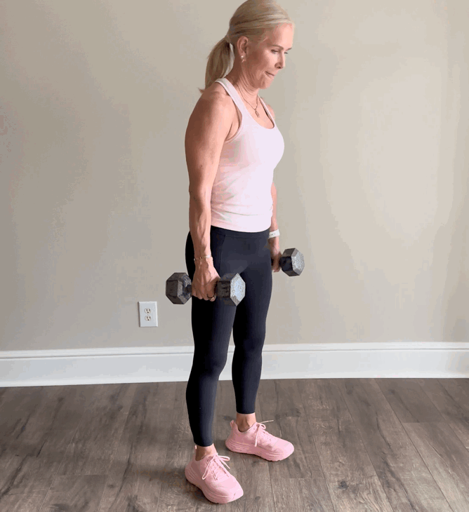 Person lifting dumbbells in home workout setting.