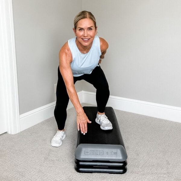 woman smiling on step platform demonstrating cardio step exercises for women over 50