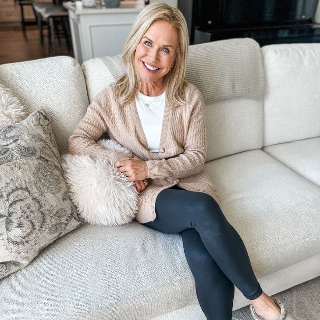 woman smiling sitting on couch showing cozy fall leggings outfit for middle aged women