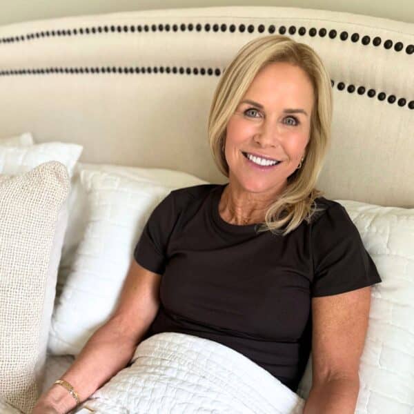 woman smiling in bed sharing sleep gadgets for women over 50