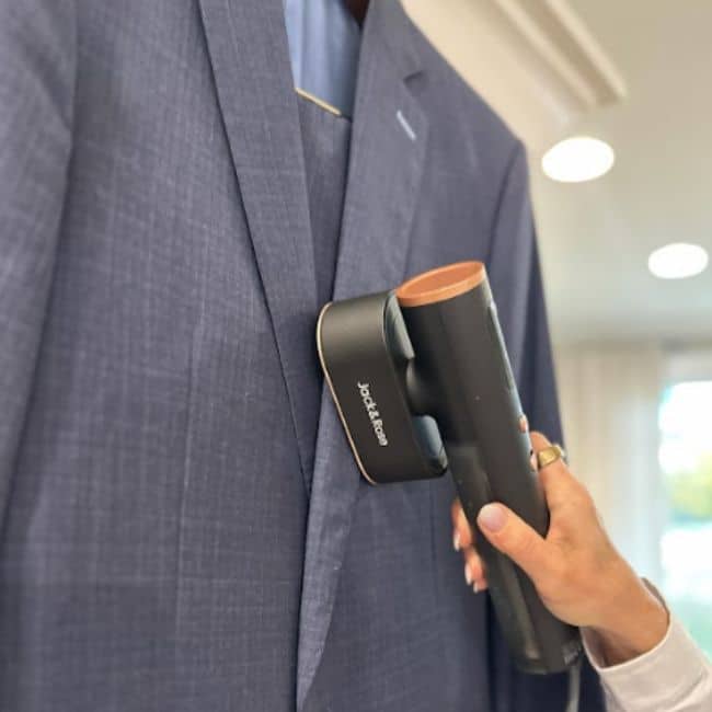 Portable travel steamer removing wrinkles from clothes in a hotel room