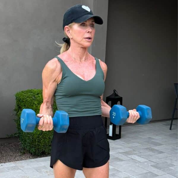 Woman over 50 slowly lowering dumbbells during eccentric bicep curls at home gym