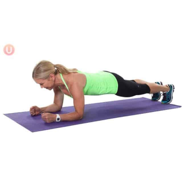 Woman holding a forearm plank position on a yoga mat building full core strength