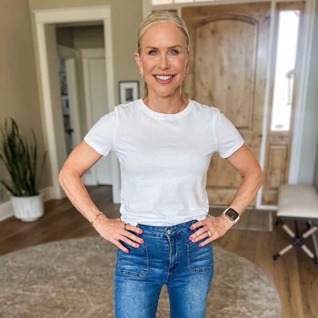 Woman over 50 wearing wide leg pants with a plain white fitted tee tucked in, creating a clean polished outfit