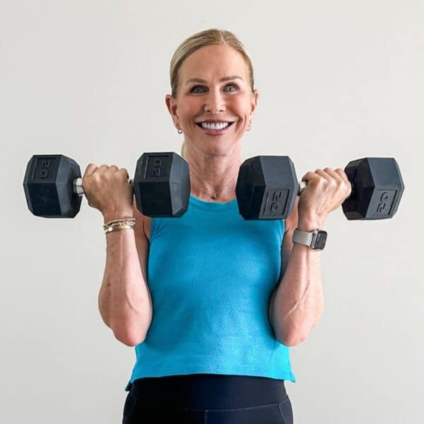 Woman over 50 doing a farmer's carry with dumbbells to build grip strength and longevity