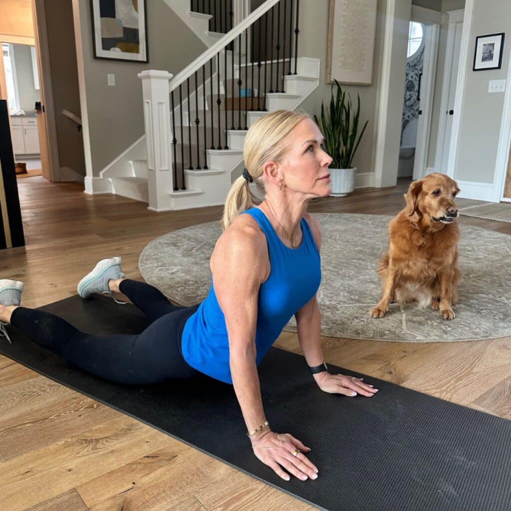 Woman in cobra pose with hips heavy on the mat and shoulders down, opening the front of the body after a walk