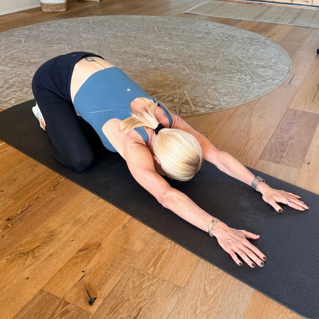 Woman resting in child&rsquo;s pose to stretch her lower back